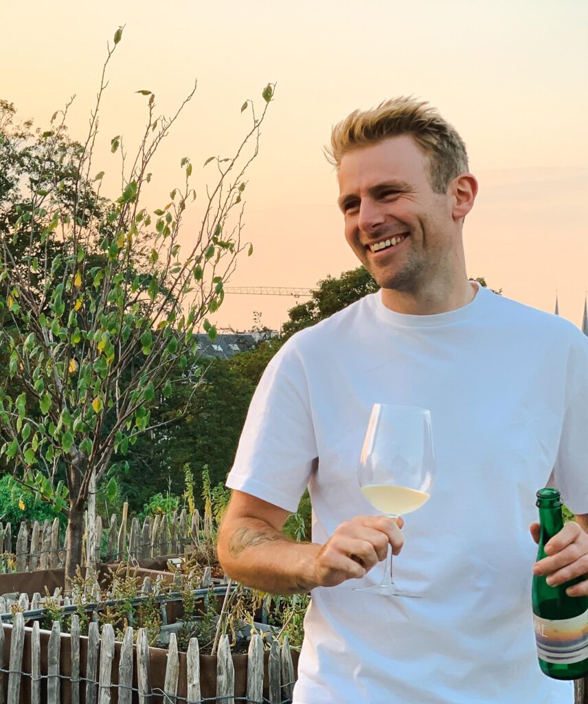 Foto van Pieter die aan het lachen is met een glas witte wijn in de hand