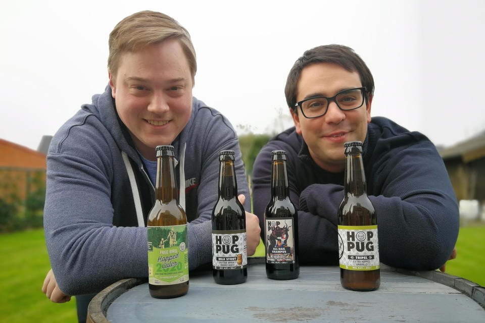 Kim & Stijn van brouwerij hoppug die rechtstaan al leunend voor enkele van hun bieren