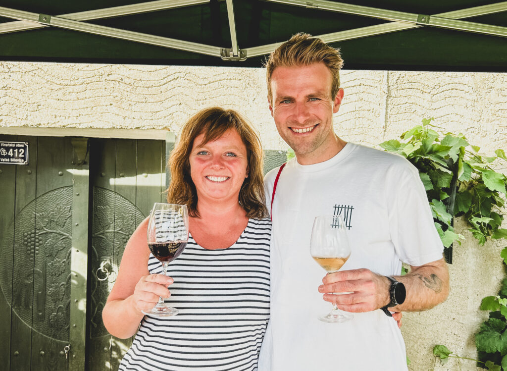 Zuzana Herzanovi, 1 van de producenten achter wijndomein "Herzanovi" en Pieter Keersmaekers van "Craft Club" die lachen met een glas wijn in de hand.